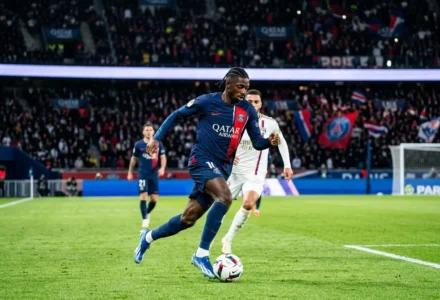 Ousmane Dembélé en action sur le terrain lors d’un match, dribbliant le ballon avec effort.