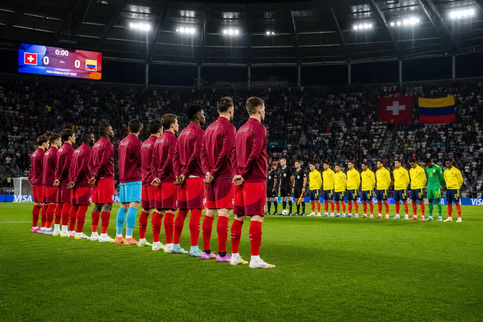 Equipe de Suisse et équipe de Colombie alignées avant le coup d’envoi, joueurs en rang sur le terrain de stade illuminé. suisse colombie quel pari choisir, pronostic et meilleures cotes à venir.