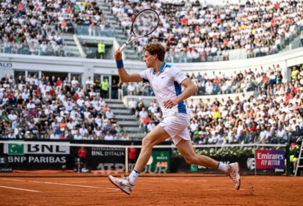 Jannik Sinner en action sur terre battue, casque levé au vent, lors d’un échange au filet pendant un match. classement atp de jannik sinner 2026.