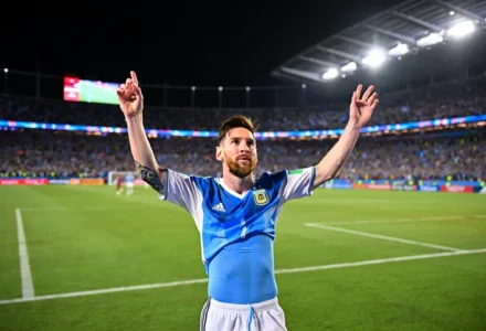 Lion de l’Argentine célébrant sur le terrain après le match, bras levés, maillot bleu et blanc, stade plein en arrière-plan. résultat argentine égypte évoqué.