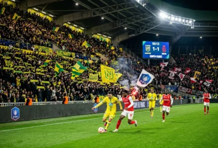 Match de football en coupe avec supporters et drapeaux jaunes et verts, joueurs en action sur le terrain. pronostic coupe de france mentionné.