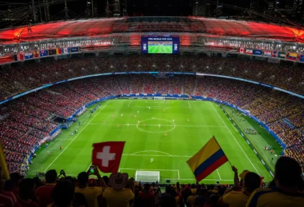 Stade bondé en coupe du monde: vue plongeante sur le terrain vert, supporters agitant des drapeaux Colombie et Suisse, ambiance festive. Résultat colombie suisse en perspective.