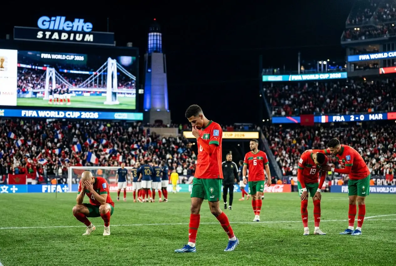 Stade Gillette lors d’un match France-Maroc, joueurs tristes sur le terrain après une défaite, écrans publicitaires et tribunes pleines en arrière-plan. résultat france maroc 2026