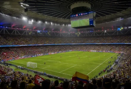 Stade plein pour Suisse-Colombie, vue aérienne du match des 8es de la Coupe du Monde 2026, tribunes colorées et terrain vert au centre.