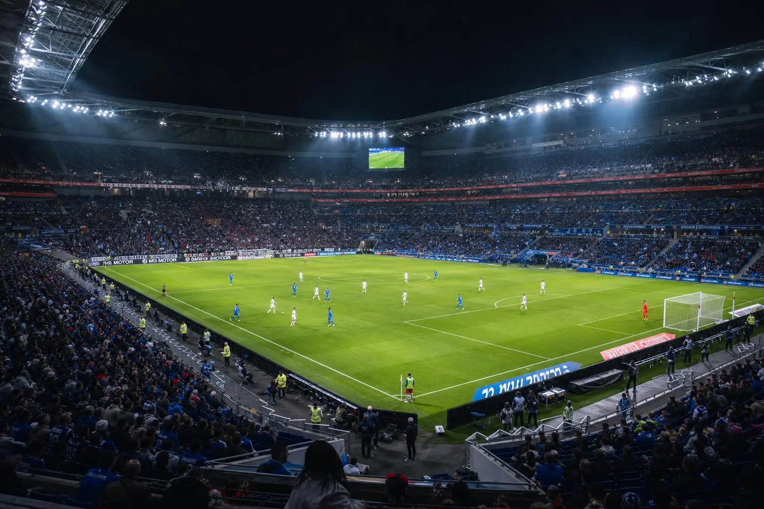 Vue d’ensemble d’un stade de football bondé éclairé la nuit, match en cours sur une pelouse verte avec joueurs bleus et blancs. pronostics ligue 1 france intégrés naturellement.