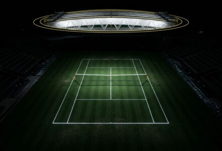 Lendrier du tournoi de Wimbledon 2026: terrain de tennis éclairé au centre du court, écrans et tribunes autour de l’aire de jeu.