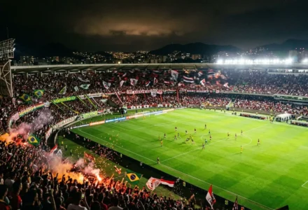 Stade bondé de supporters avec drapeaux, ambiance nocturne et feux d’artifice; match de football se disputant sur un gazon vert. pronostic brésil serie b intégré naturellement dans le contexte.