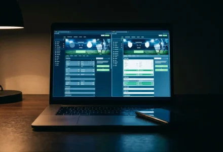 Bwin ou Betclic comparaison : écran de laptop affichant deux interfaces de paris en ligne, tablette et lumière douce en arrière-plan